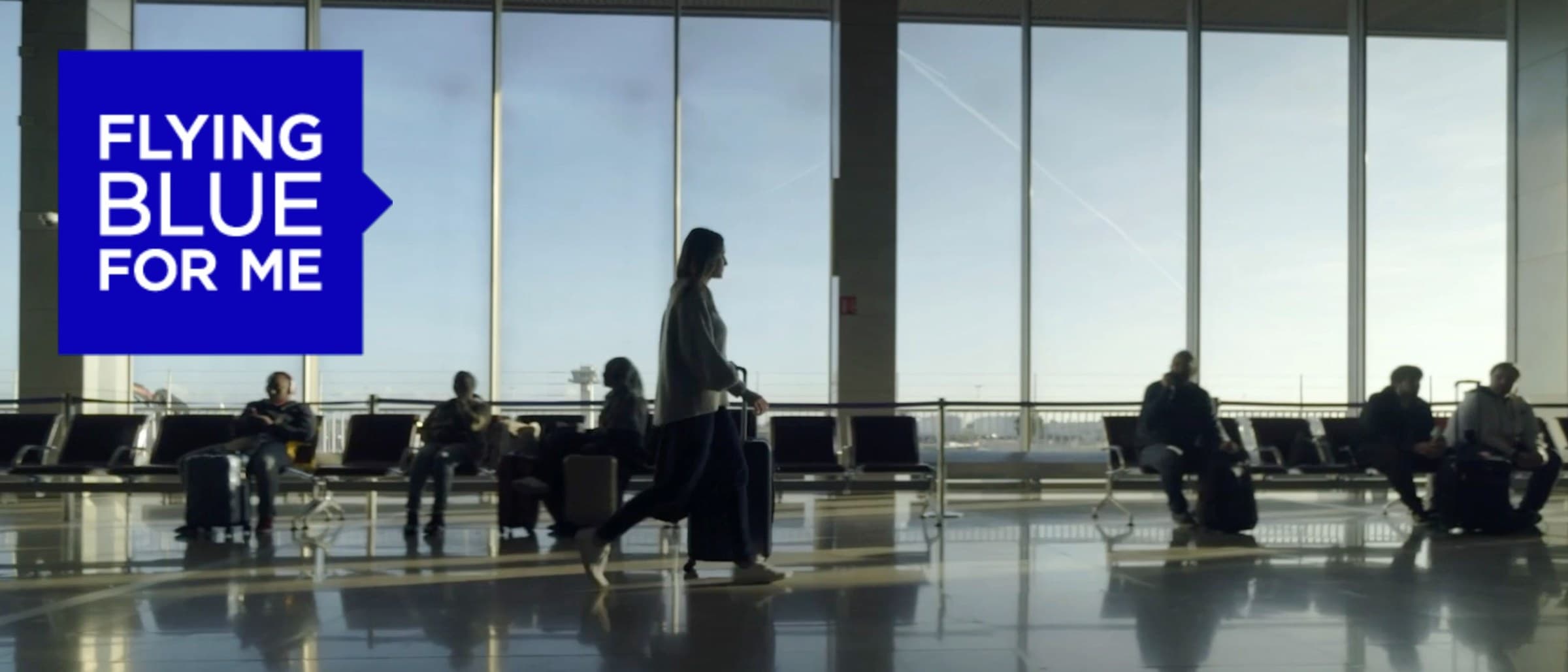 Travellers waiting at an airport gate, with a 'Flying Blue for me' panel alongside